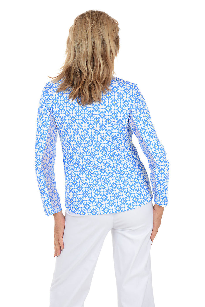 Woman wearing a blue floral patterned shirt on a white background. Back shot.
