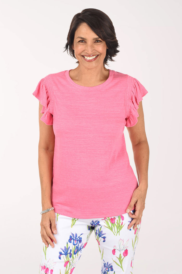 Woman wearing a pink top and floral pants on a white background