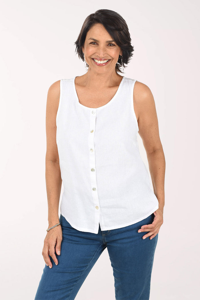 Woman wearing a white sleeveless blouse and blue jeans on a light pink background