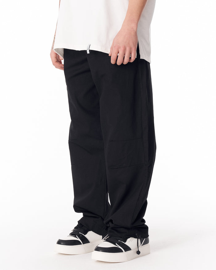 Martin Valen black wide-leg trousers, mid shot showing elastic waistband partly hidden under a white t-shirt