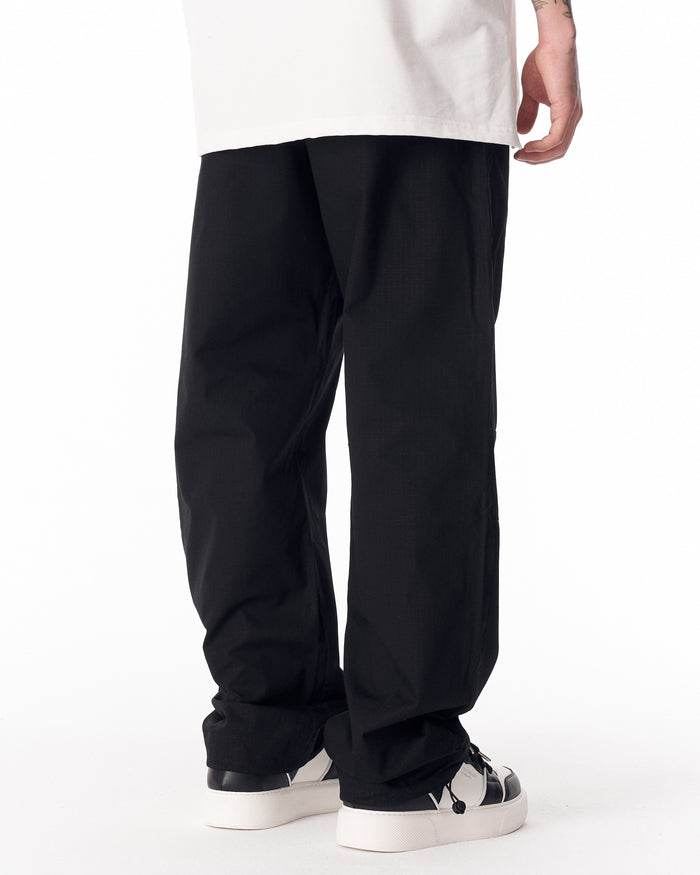 Martin Valen black wide-leg trousers with adjustable cuff, rear mid-leg view showing right leg