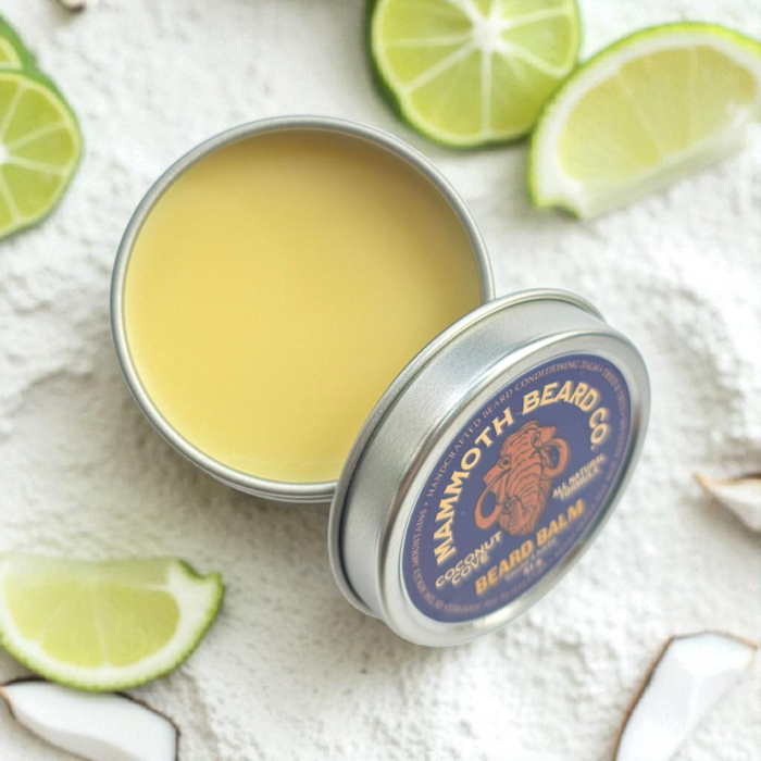 Mammoth Beard Co Coconut Cove Beard Balm on a sand background with coconut, lime, and bay leaves.