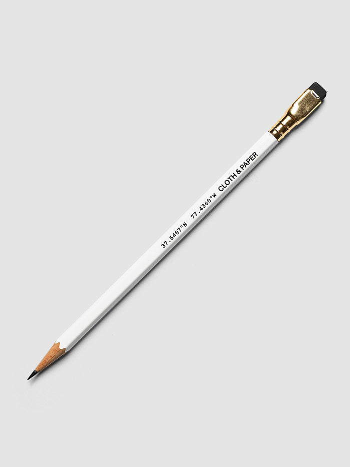 A single white Blackwing pencil with a gold ferrule and black eraser, shown diagonally on a light gray background. The pencil has coordinates on it and the Cloth & Paper logo.