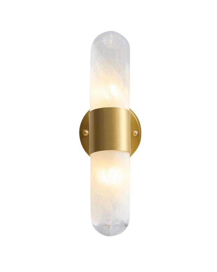 Vertical brass wall sconce with a softly glowing textured glass cylinder, secured at the center by a brushed brass band and mounted on a round brass backplate, emitting warm ambient light.