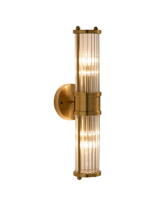 Brimsley II wall sconce featuring a vertical brass mount with ripple-textured clear glass panels and two glowing light sources, creating a warm, refined ambiance.