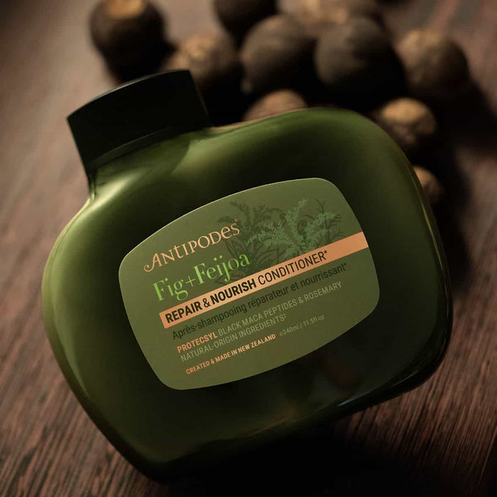 Green bottle of Antipodes Fig + Feijoa Conditioner on a wooden surface.