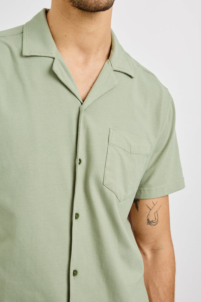 Flint Collared Button Shirt with Short Sleeves and a Chest Pocket in Sage Colorway. Front View Shown on Model.