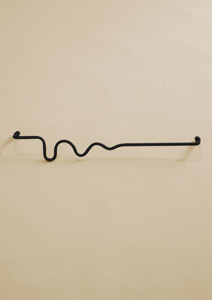 Black-colored towel bar with a wavy organic shape, shown in a studio setting on a neutral background.