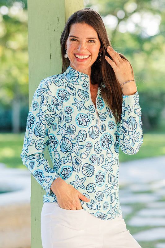 Woman wearing a blue floral patterned shirt with a blurred green outdoor background