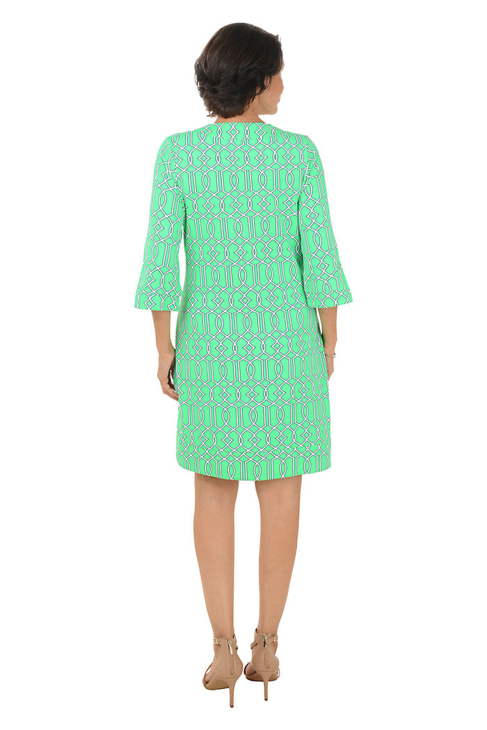 Woman wearing a green patterned dress on a white background. Back shot.