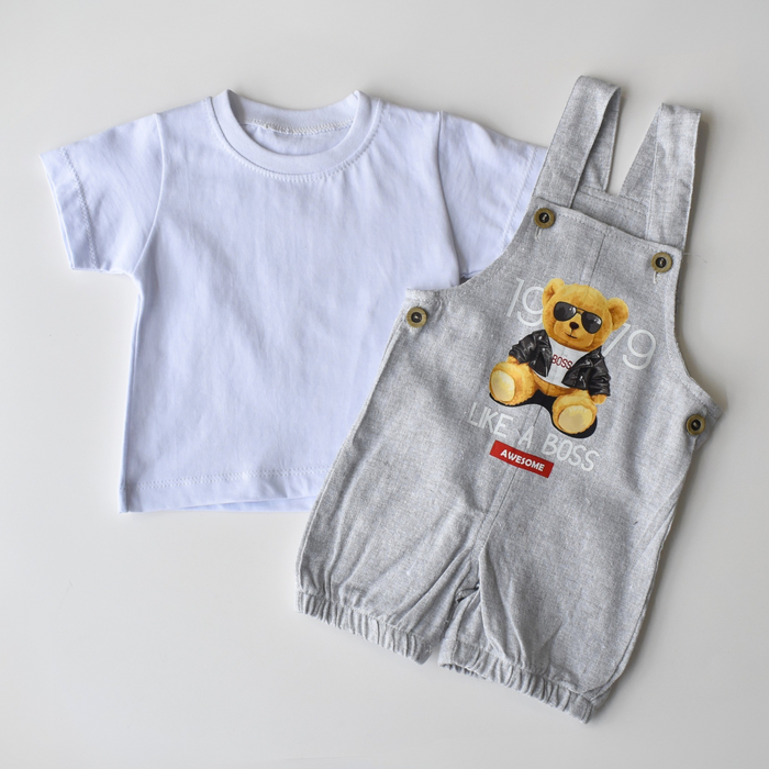 Two-piece baby boy outfit featuring a plain white short-sleeve T-shirt paired with grey romper overalls printed with a teddy bear in sunglasses and jacket.