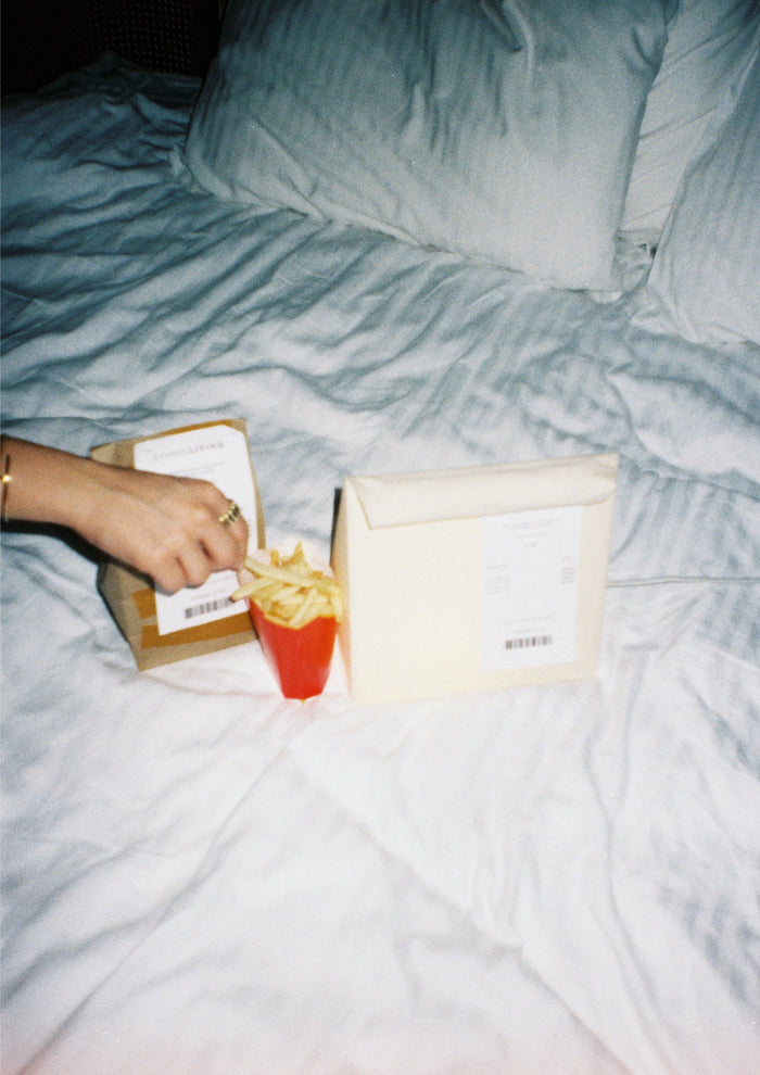 Lunch Bag Lamp styled on a bed with takeout packaging and French fries.