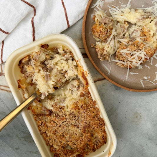 Creamy pasta bake with sausage and crispy breadcrumb topping, served in eco container and on plate