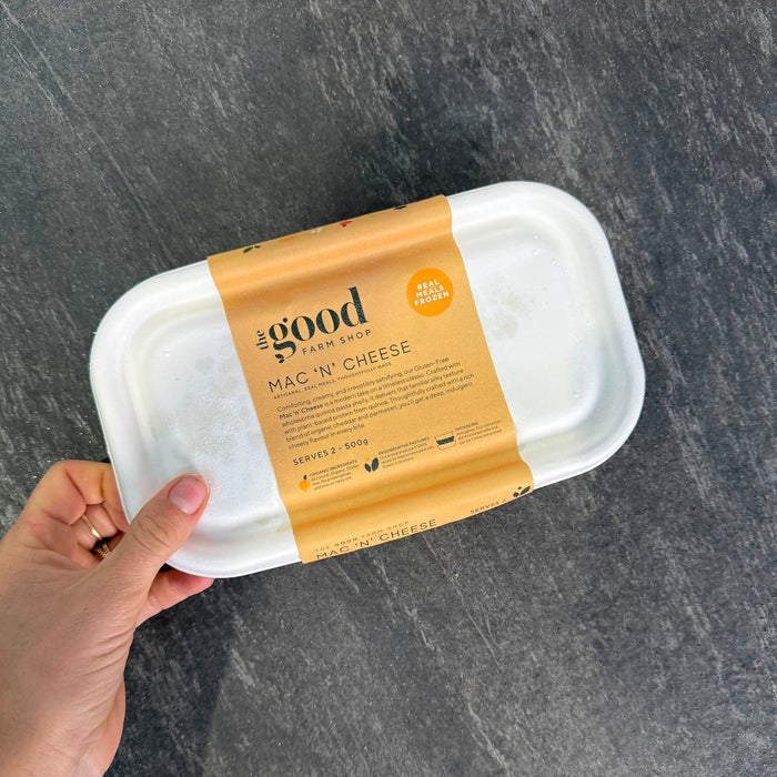 Gluten-Free Mac 'N' Cheese from The Good Farm Shop, organic and ready to heat, held in hand over dark surface