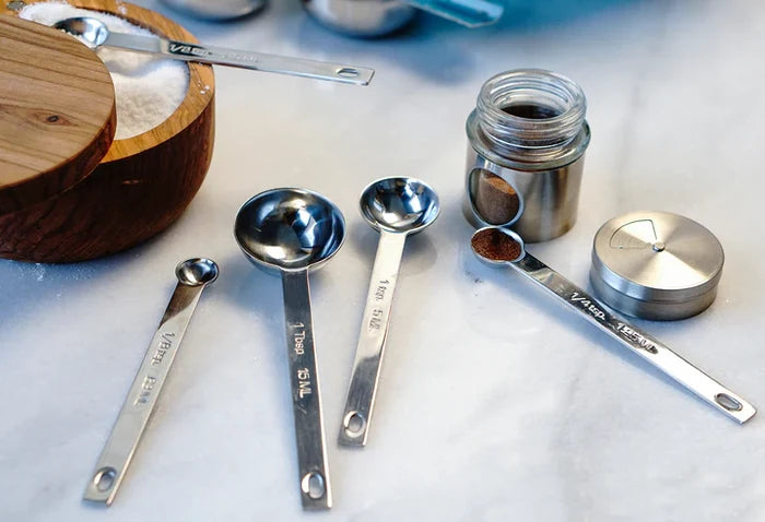 Set of metal measuring spoons and cups on a marble surface