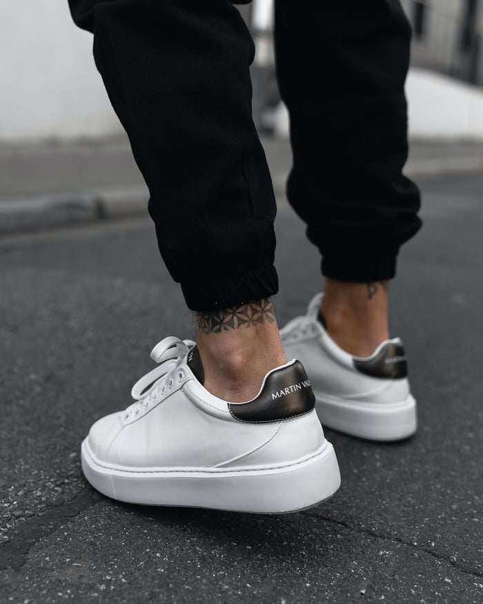 Martin Valen Iconic men's white-and-black casual sneakers, rear-side outdoor view on feet highlighting black logo heel tabs
