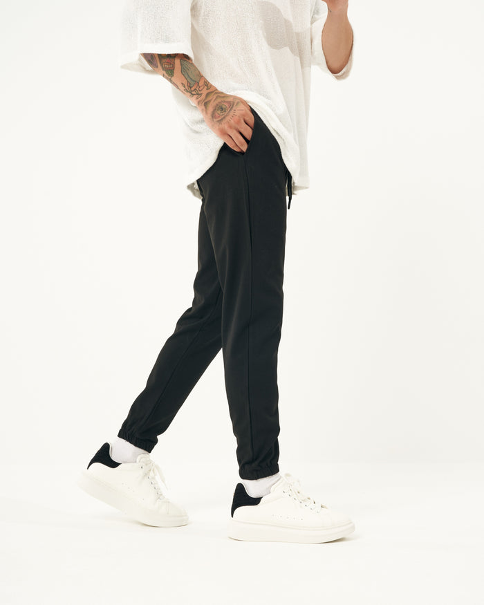 Martin Valen black men's jogger with elastic cuffs, close front view showing legs and white sneakers