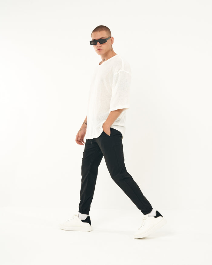 Martin Valen men's black jogger with elastic cuffs, three-quarter walking view showing loose fit and cuff detail