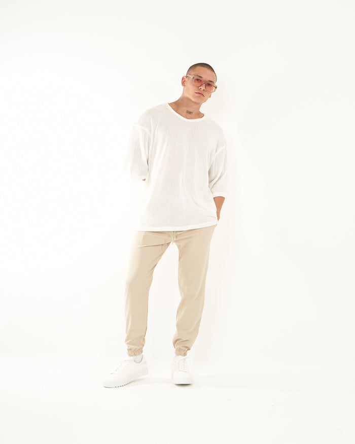 Martin Valen men's beige elastic-cuffed loose jogger, full-length view with model leaning and hands in pockets