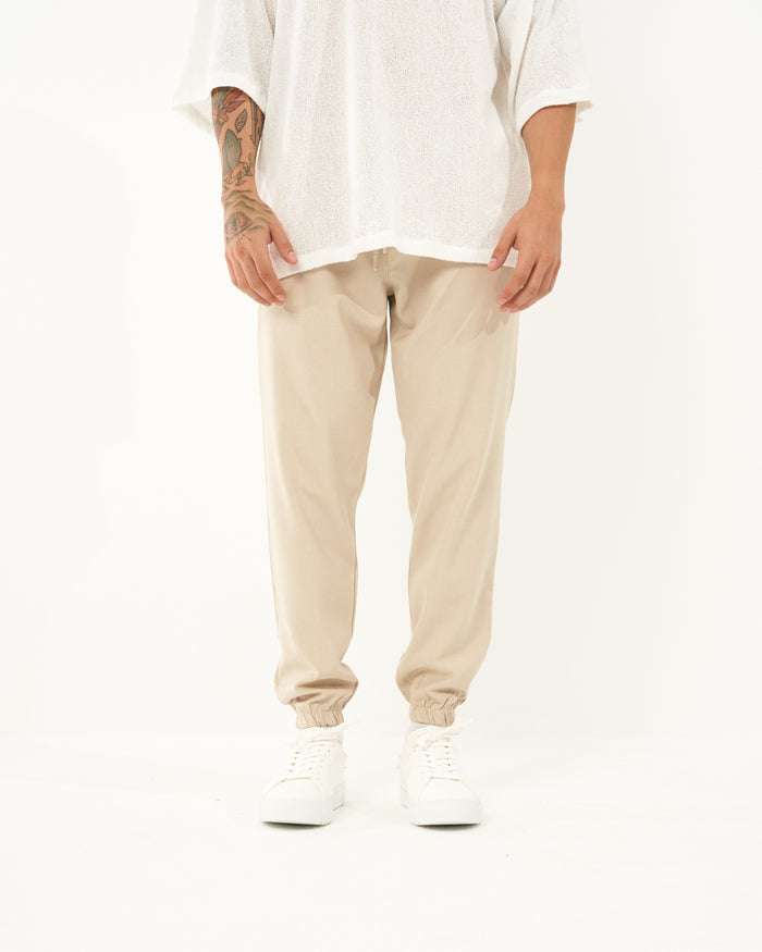 Martin Valen men's loose-fitting beige jogger, front view from waist to shoes showing elastic cuffs and drawstring waist