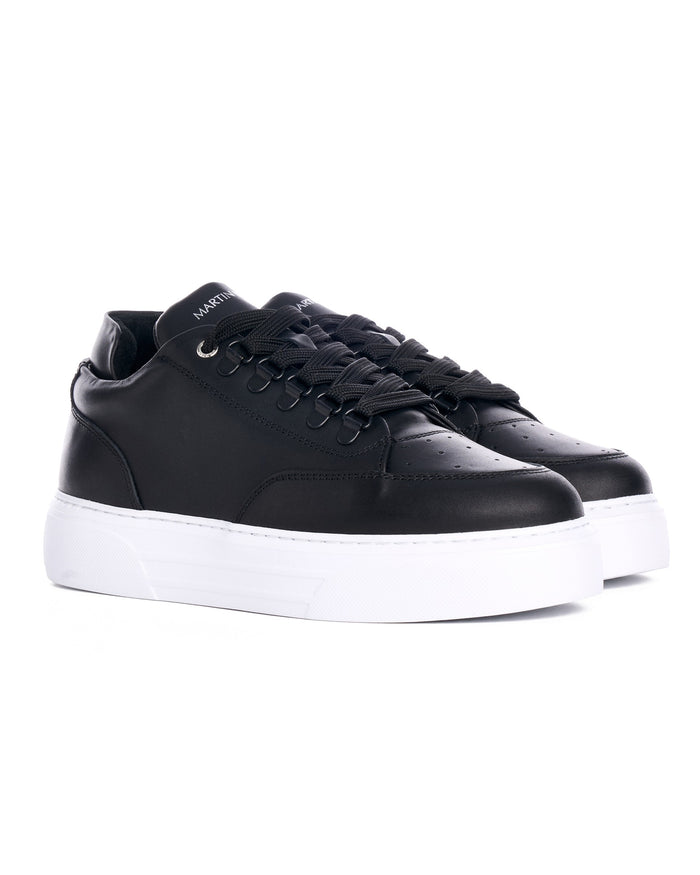 Pair of Martin Valen black low-top sneakers angled view, branded tongues and woven laces visible