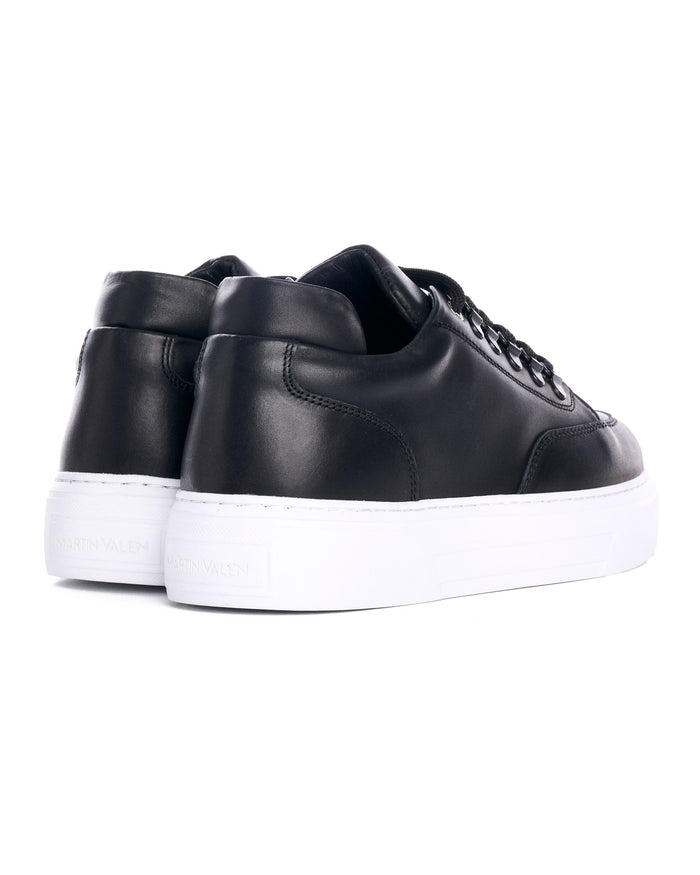 Martin Valen black low-top sneakers three-quarter front view, perforated toe detail and visible white platform sole