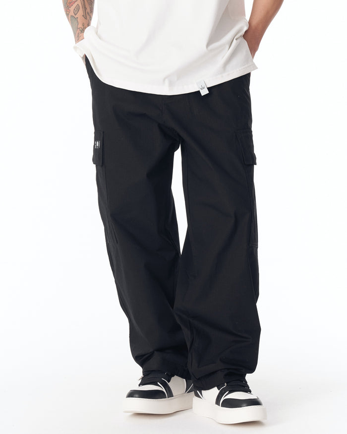 Martin Valen black cargo pants, rear view showing wide legs, dropped hem and white platform sneakers
