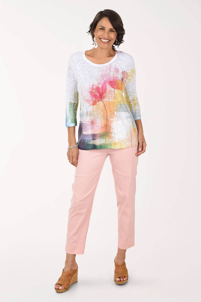 Woman wearing a colorful top and pink pants on a white background