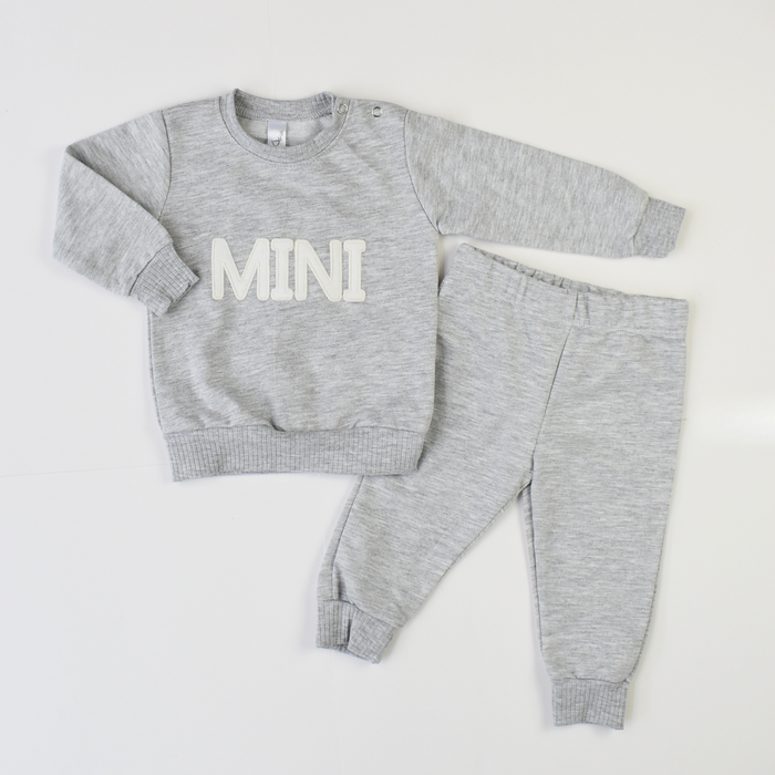 Grey baby tracksuit set with long-sleeve sweatshirt printed “MINI” and matching jogger pants.