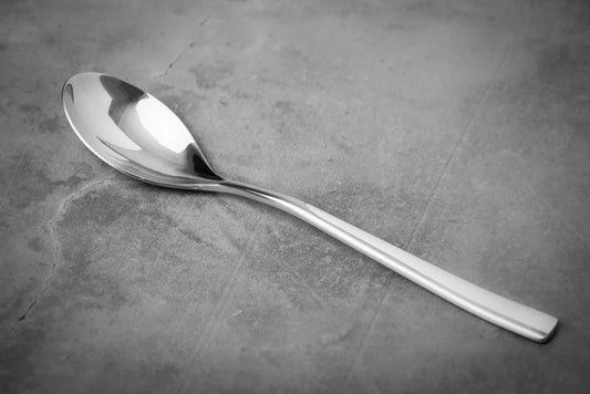 Silver Titanium spoon on a textured gray surface.