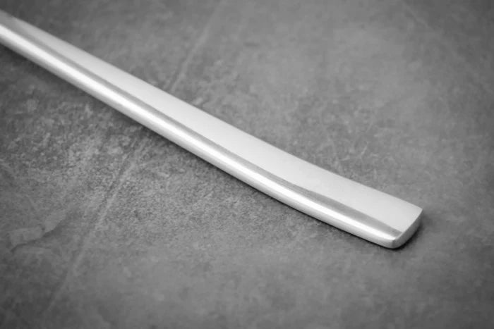 Titanium spoon handle close-up on a textured gray surface.