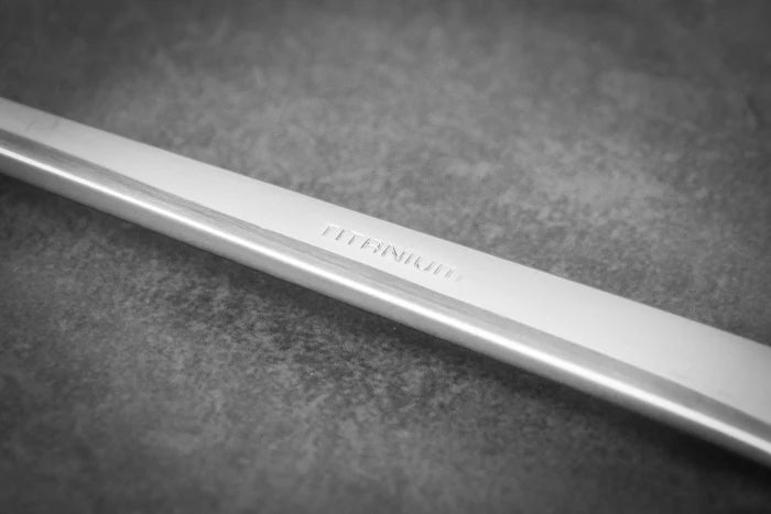 Titanium spoon closeup with engraved "Titanion" logo in handle on grey surface background.