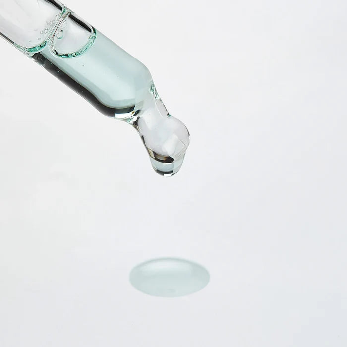 Dropper releasing a clear, light blue serum drop above a droplet on a white background for Oligoforce Advanced Wrinkle & Dark Spot Correction Moisturizing Serum with Oligomer | Phytomer skincare.