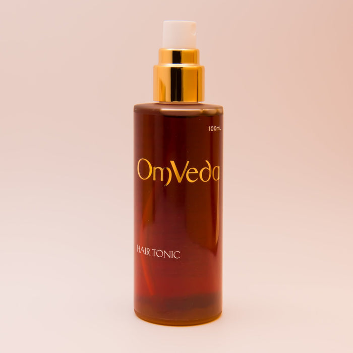 OmVeda hair tonic bottle with gold pump, amber formula, 100 ml