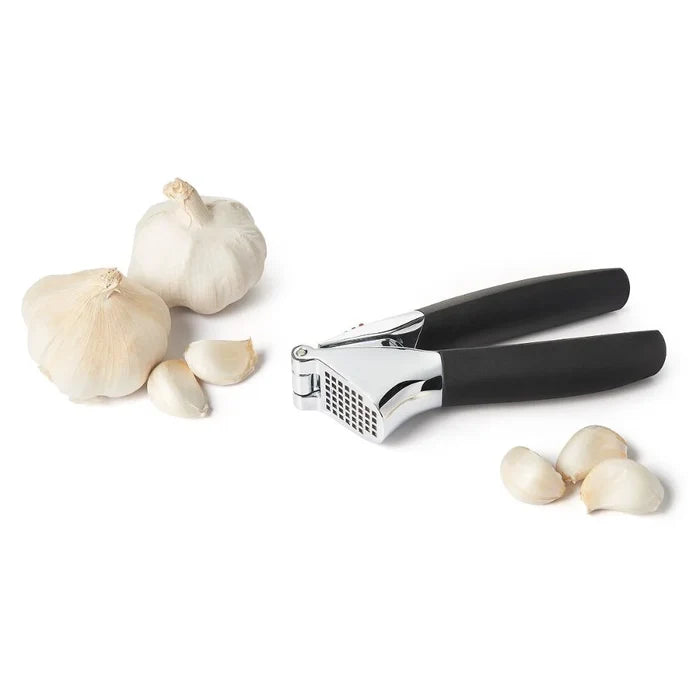 Garlic press with garlic cloves on a white background