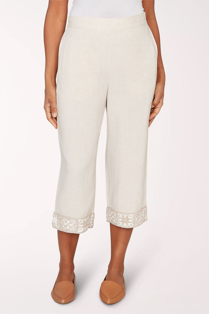 Person wearing white pants with lace cuffs on a white background
