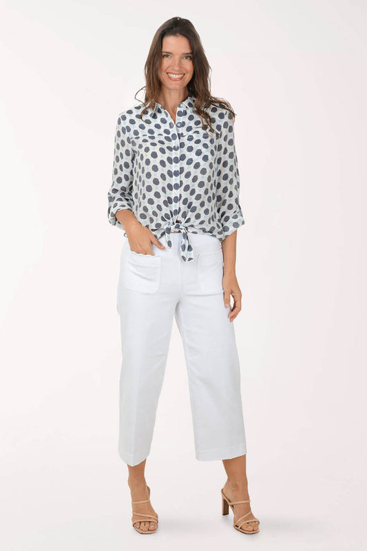 Woman wearing a patterned blouse and white pants on a white background
