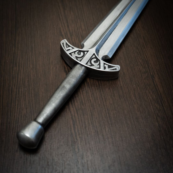 Decorative sword with ornate hilt on a wooden surface