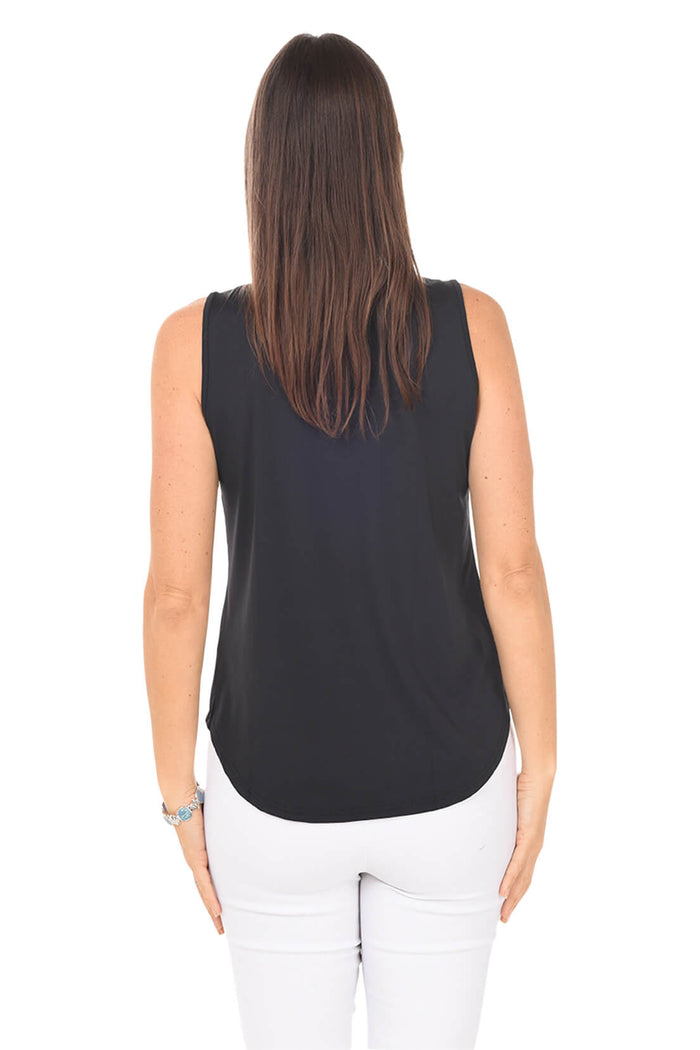 Woman wearing a black sleeveless top and white pants on a white background. Back shot.