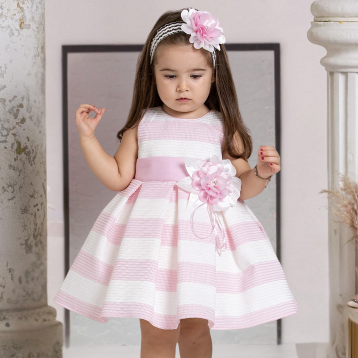 Little girl wearing pink and white striped dress with flower belt and matching flower headband