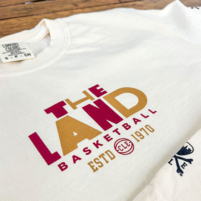 White sweatshirt with 'The Land Basketball' text on a wooden surface