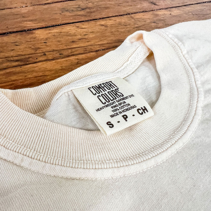 Close-up of a beige sweatshirt with a label on a wooden surface