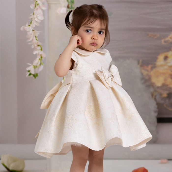 Little girl wearing an ivory dress with bow detail