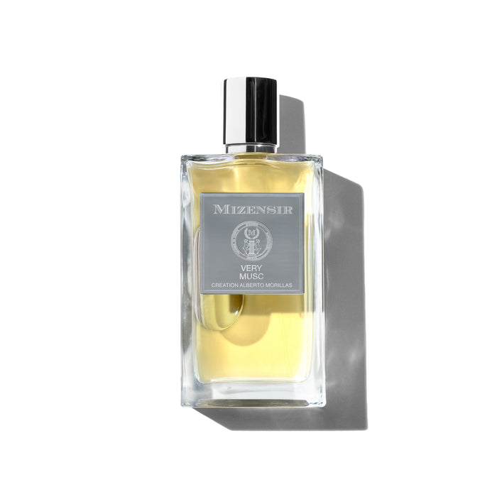 A clear glass perfume bottle with a sliver label reading "Mizensir Very Musc" and a sleek silver cap. The liquid inside is a light yellow.