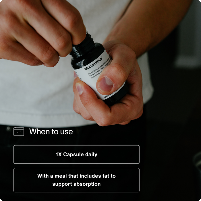 Person opening a bottle of supplements with text instructions for Vitamin D3 5000 IU recommending one capsule daily taken with a meal that includes fat to support absorption.